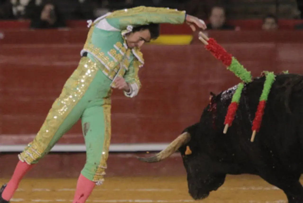 El torero El Fandi clava las banderillas en el lomo del toro, un momento de gran tensión en la plaza.