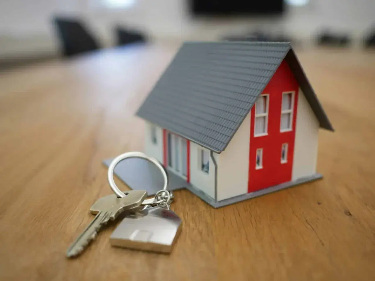 Une clé et un porte-clés en forme de maison, symbolisant le projet de vendre sa maison.