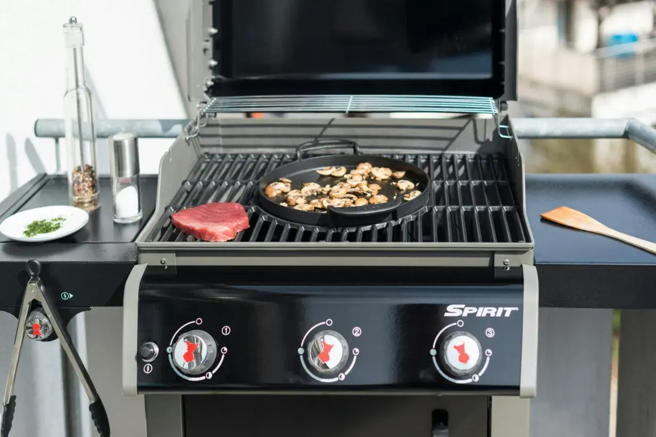 En portabel gasolgrill bäst i test förbereds med en rå biff och champinjoner. Kryddkvarn och saltkaret står redo.