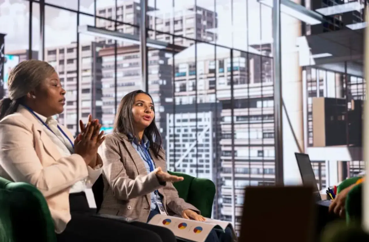 Two women in a meeting discuss business strategy, perhaps inspired by their organizational management degree.