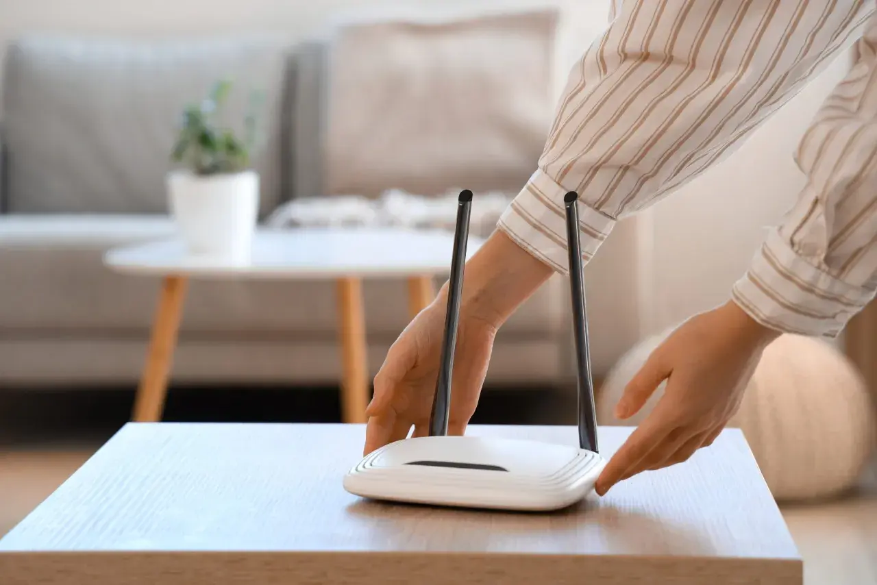 Ręce dotykają routera Wi-Fi. Chcesz wiedzieć, jak sprawdzić hasło do Wi-Fi?