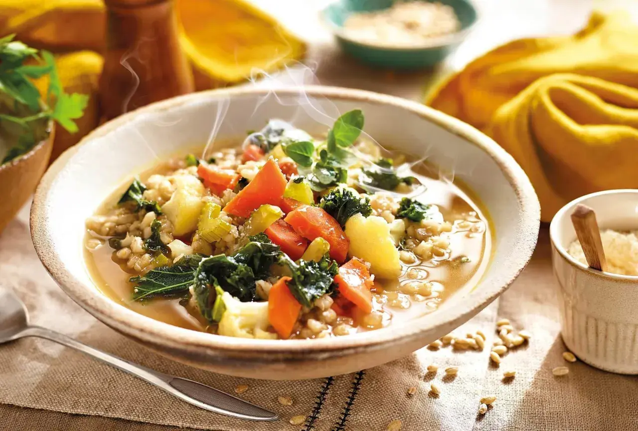 Un humeante tazón de sopa de cebada con kale, zanahorias y patatas. ¡Perfecto para tus recetas con kale!