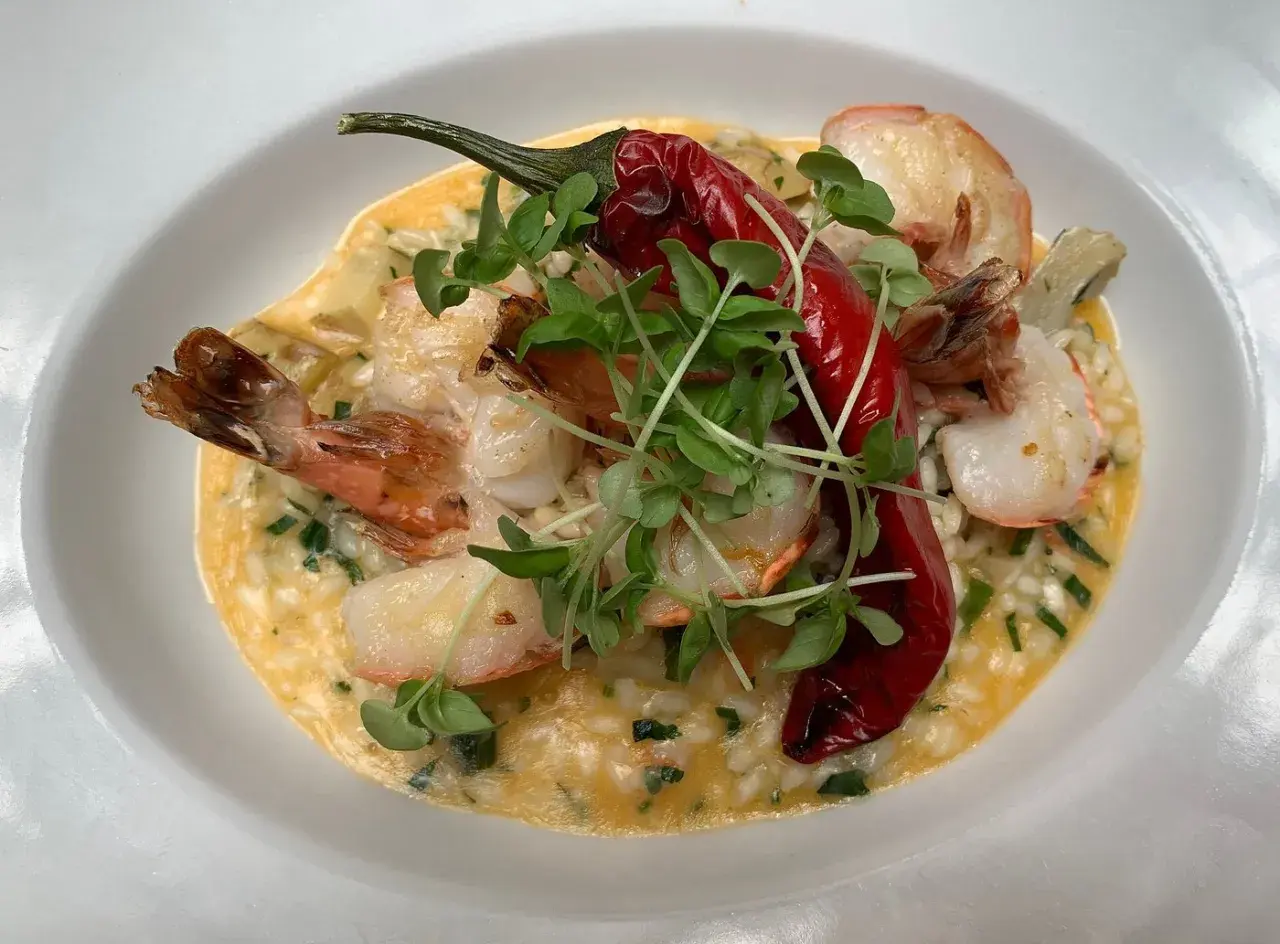 Kremowe risotto z krewetkami, ozdobione papryczką chili i kiełkami. Idealne danie, do którego użyto aromatycznego bulionu do risotto.