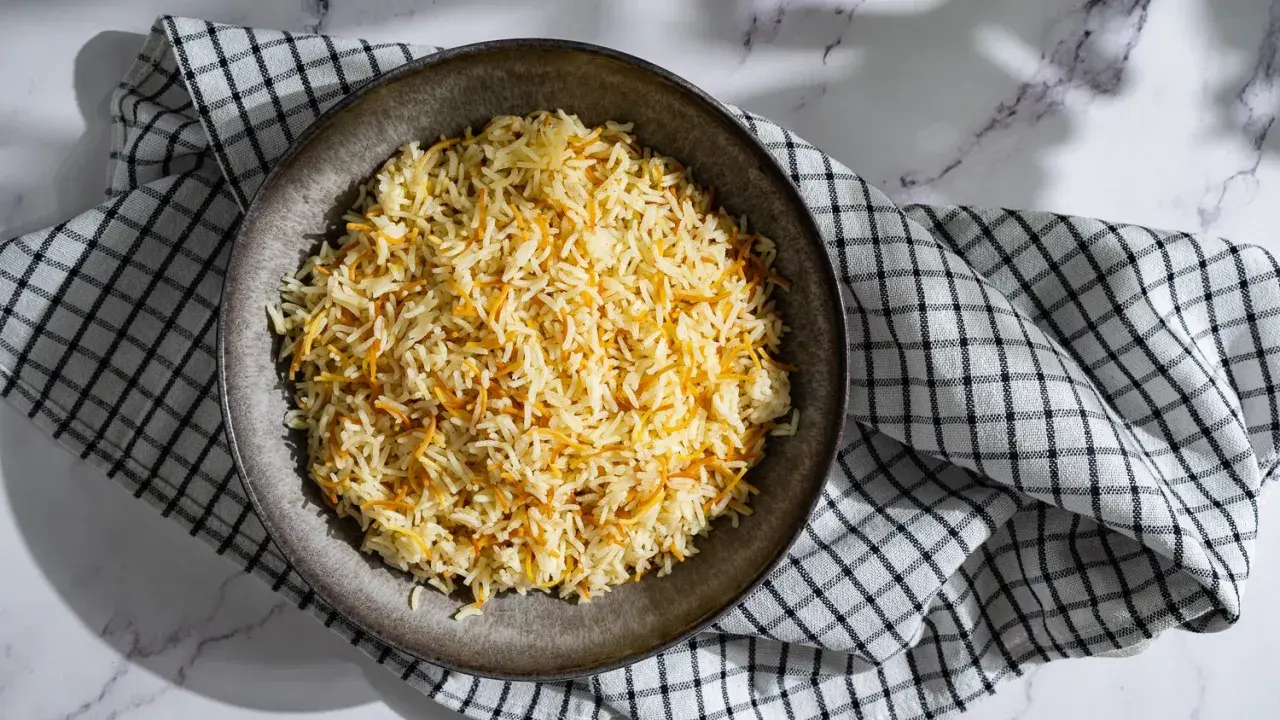Un plat de riz libanais, parsemé de vermicelles dorés, servi sur une serviette à carreaux.