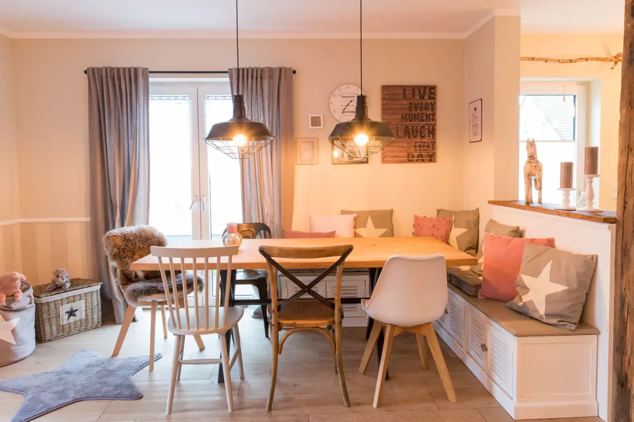 Gemütliches Esszimmer gestalten: Holztisch, Bank mit Kissen, verschiedene Stühle und Wanddeko schaffen einladendes Ambiente.