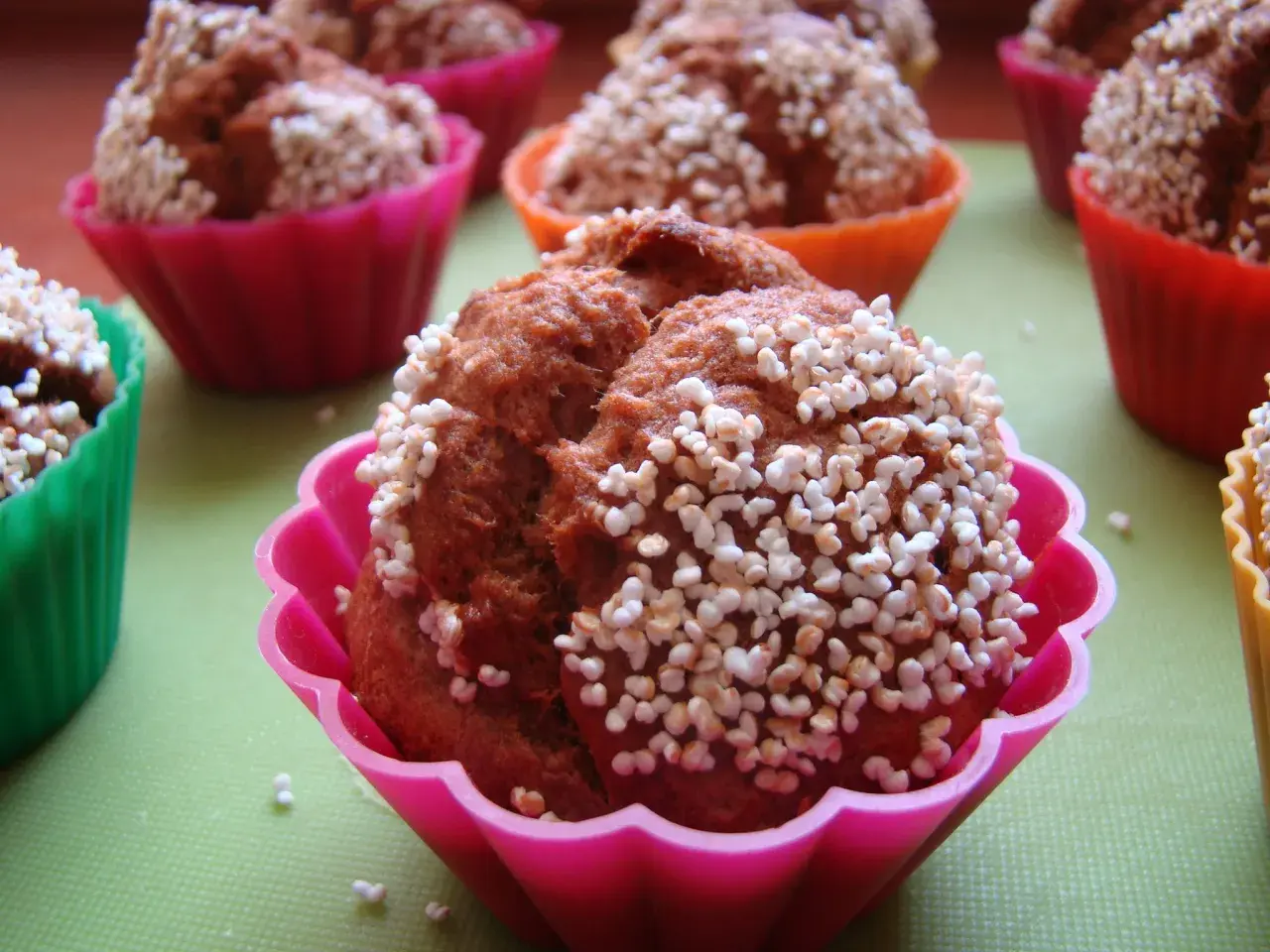 Pyszne muffinki bananowe w kolorowych foremkach, posypane chrupiącymi perełkami. Idealne na deser!