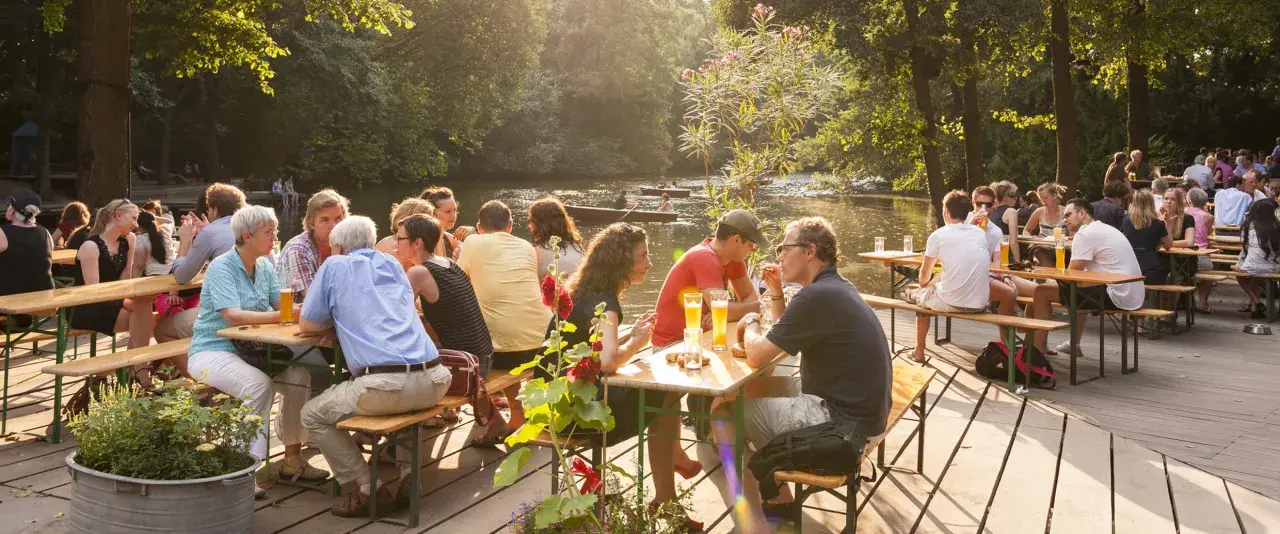 Menschen genießen das Leben im cafe am neuen see. Sie sitzen an Holztischen, trinken Bier und unterhalten sich. Im Hintergrund fließt ein ruhiger Fluss.