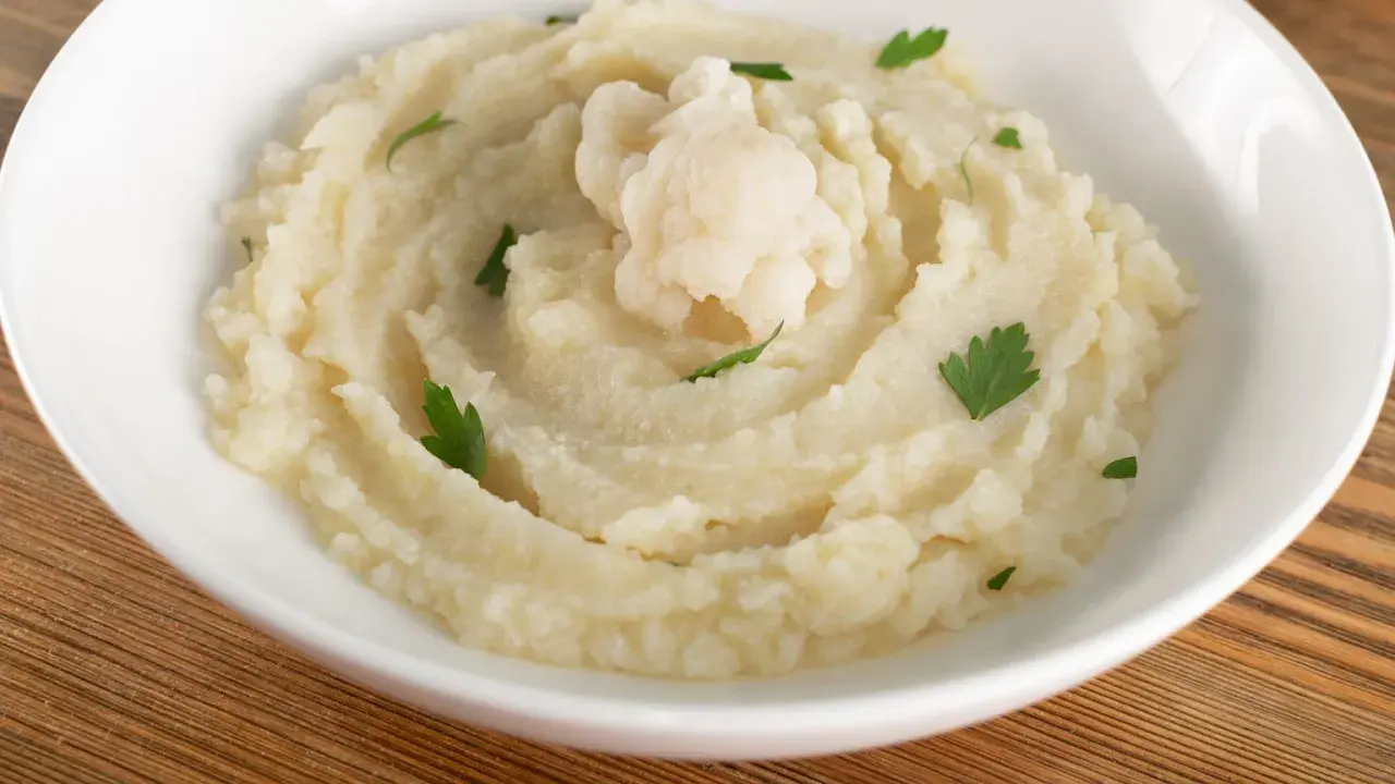 Aksamitne puree z kalafiora, udekorowane gałązką świeżej natki. Idealne jako lekki dodatek do obiadu.