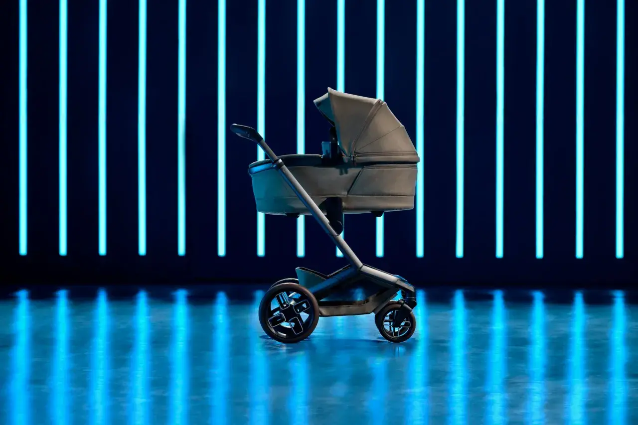 Elegancki wózek dziecięcy Maxi Cosi Fame na tle neonowych, niebieskich świateł.