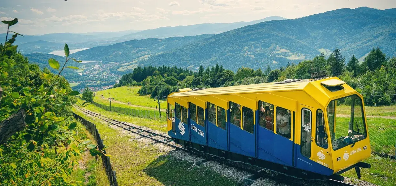 Kolejka linowo-terenowa "Góra Żar" wjeżdża na szczyt, oferując pasażerom malownicze widoki na Beskidy.