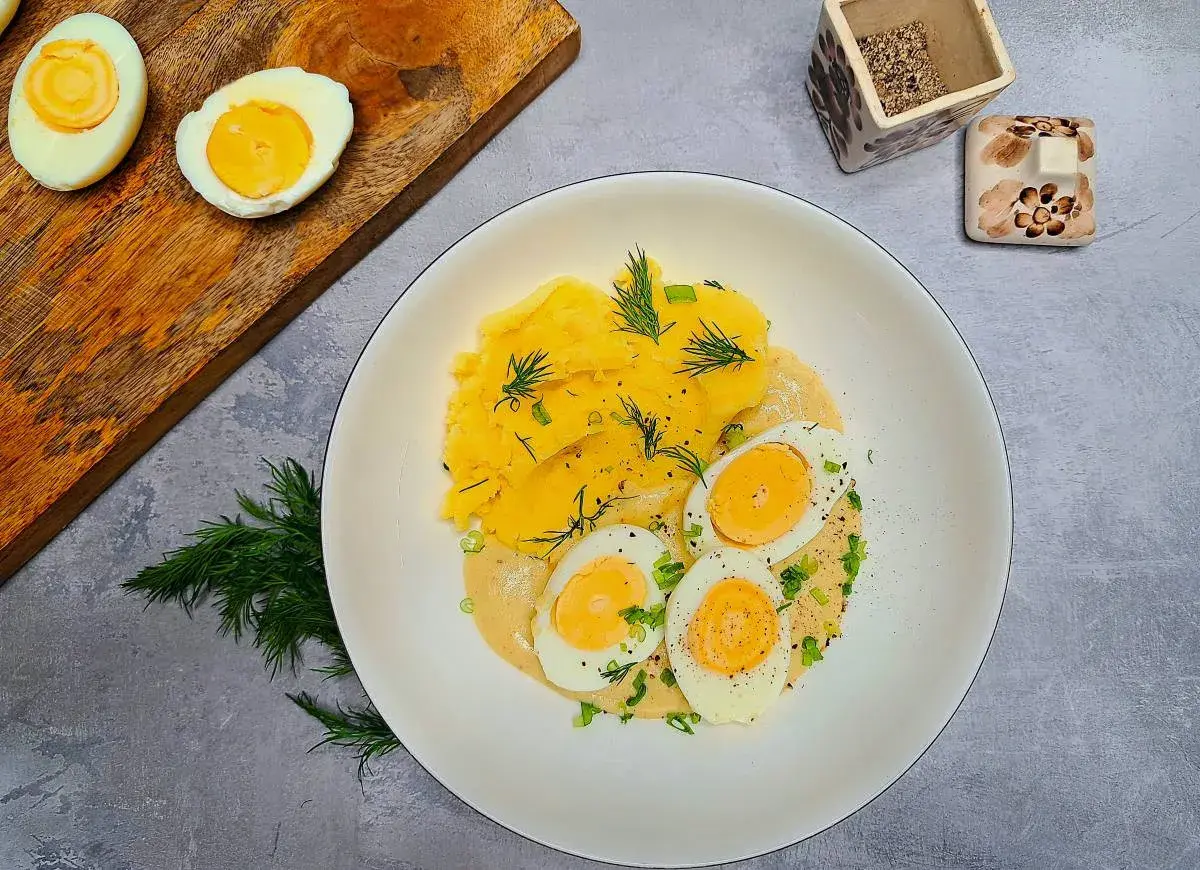 Jajka w sosie musztardowym z puree ziemniaczanym, udekorowane koperkiem i szczypiorkiem. Pyszne danie na obiad.
