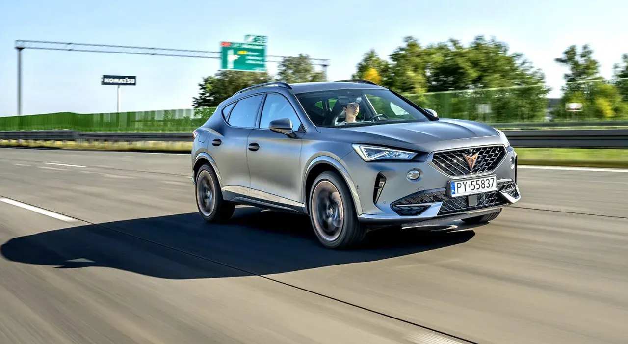 Srebrna karoseria sportowego SUV-a sunie po autostradzie.