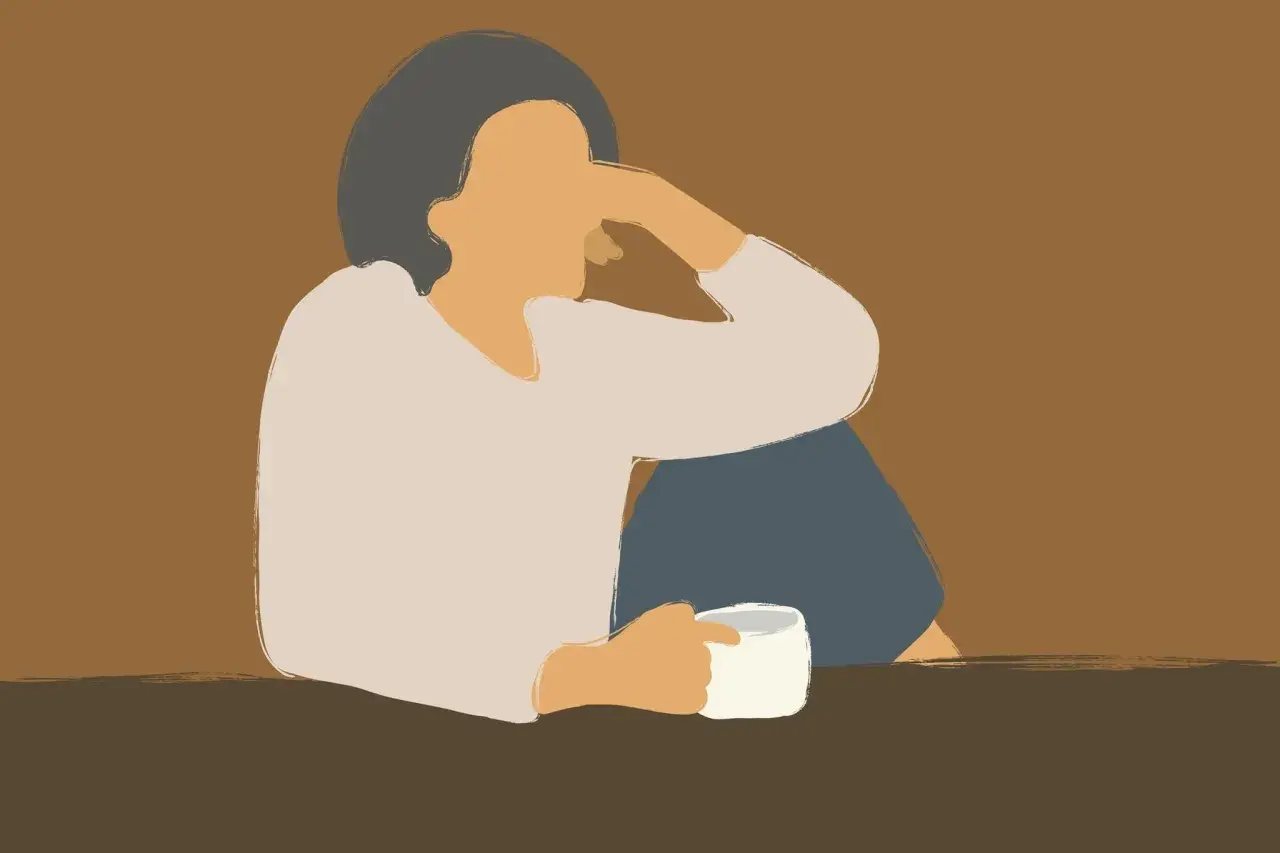Eine Person sitzt allein mit einer Tasse Kaffee, die Arme um die Knie geschlungen. Die Haltung und der Ausdruck deuten auf eine lieblose Ehe im Alter hin, voller Einsamkeit.