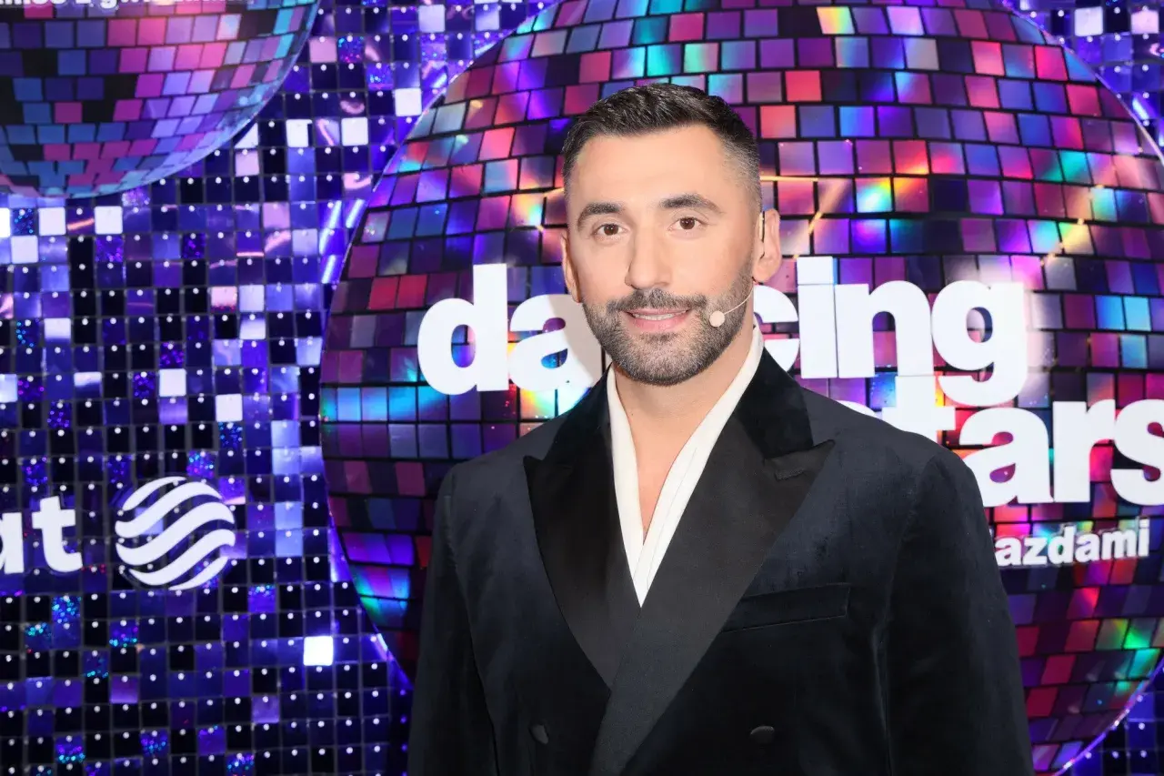 Maserak, ile lat ma? Uśmiechnięty mężczyzna w czarnym smokingu na tle błyszczącej sceny "Dancing with the Stars".