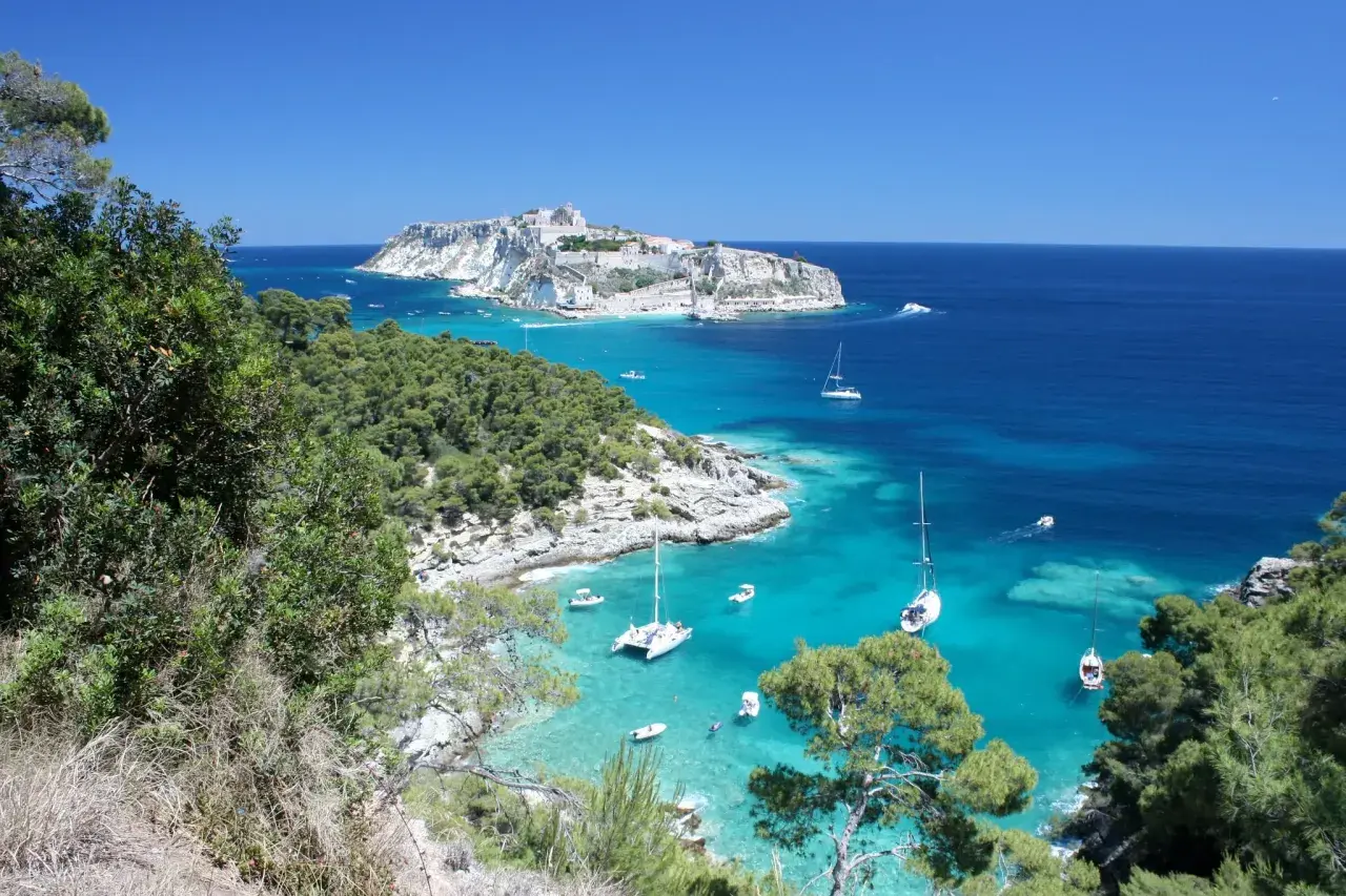 Vista mozzafiato di San Nicola di Tremiti, con il castello in lontananza e barche a vela nelle acque cristalline. Perfetto per scoprire le cose da fare a San Nicola di Tremiti.