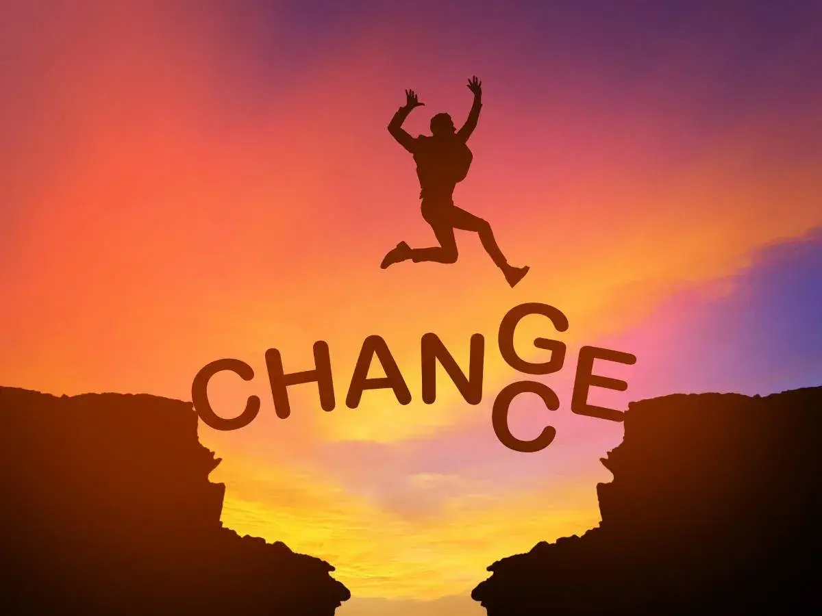 Sylwetka skacze przez przepaść, nad napisem "CHANGE". Jak mówiły Oprah Winfrey cytaty, zmiana jest kluczem do rozwoju.