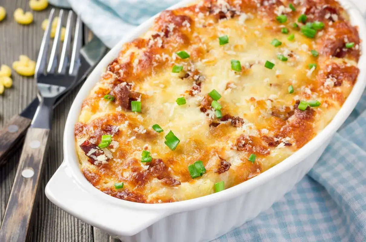 Zapiekane mac and cheese z chrupiącym serem i zieloną cebulką, gotowe do podania.