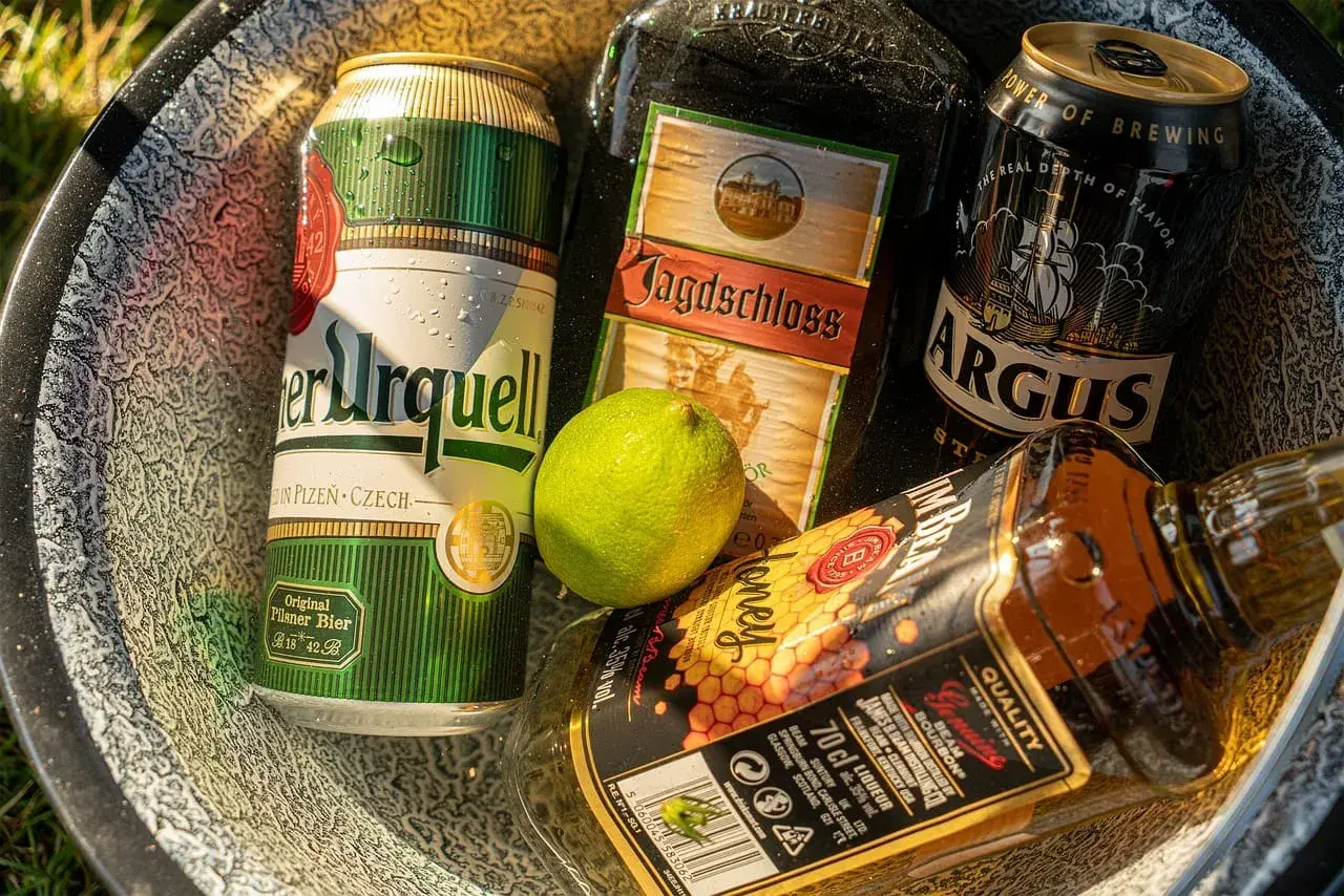 Puszki piwa i butelka whiskey w misce. Zastanawiasz się, ile chmielu do piwa?