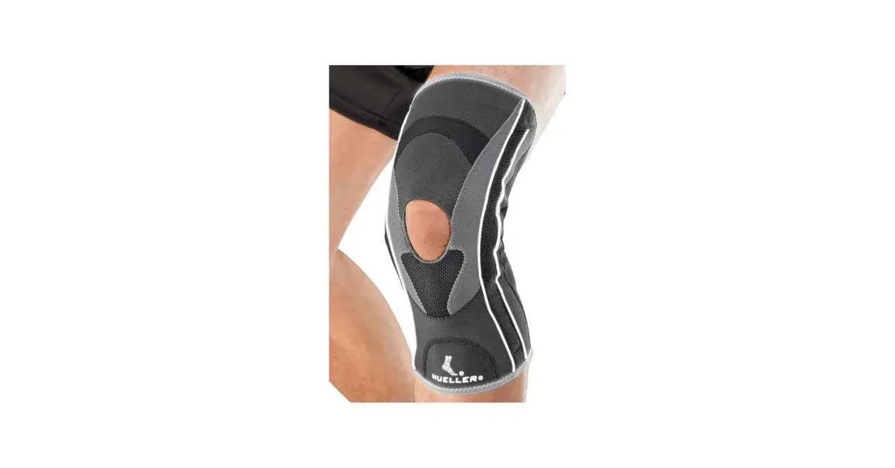 Szary stabilizator kolana Mueller HG80 z otworem na rzepkę, na nodze.