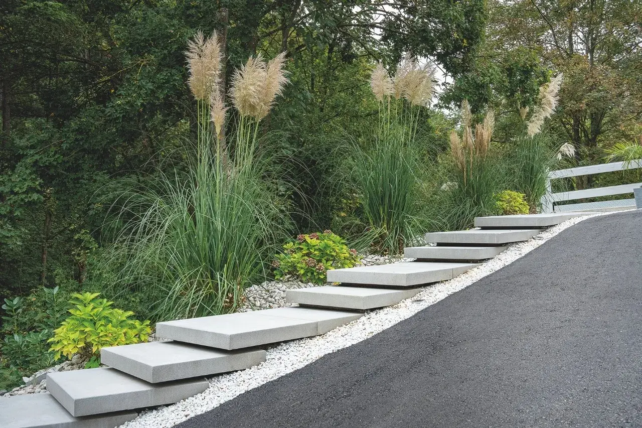 Moderne Treppe aus trockenbeton-Platten, umgeben von Ziergräsern und Kies.