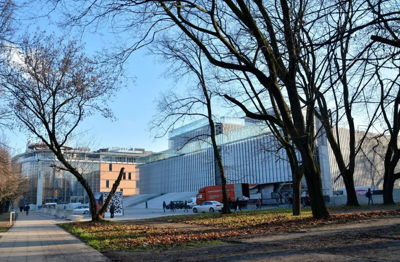 Nowoczesny budynek Centrum Spotkania Kultur na placu teatralnym w Lublinie, otoczony drzewami.