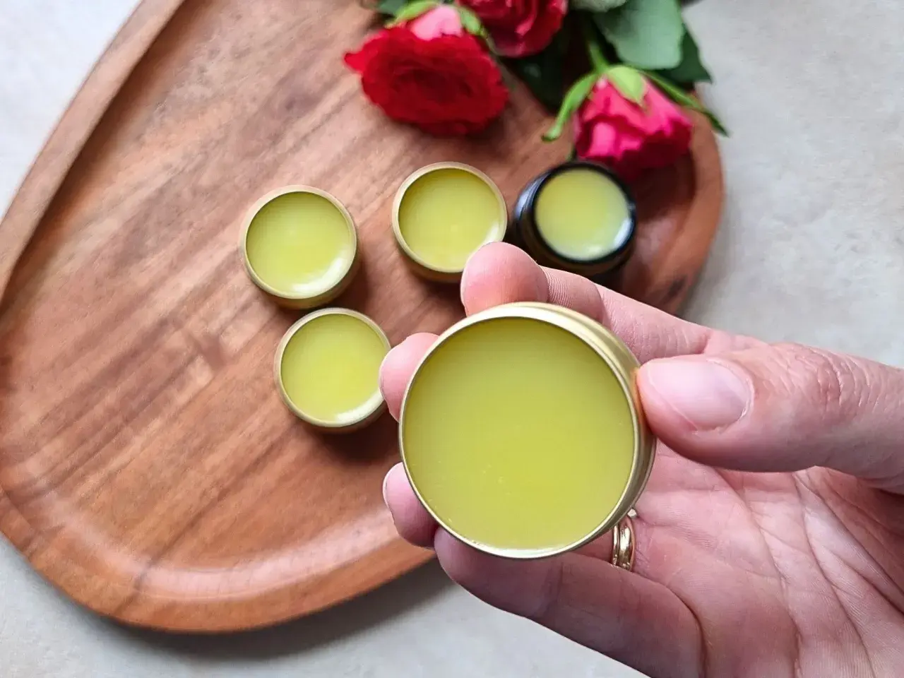 Małe, złote pojemniczki z zielonym balsamem, idealne do domowej produkcji perfum. Różane akcenty dodają uroku.