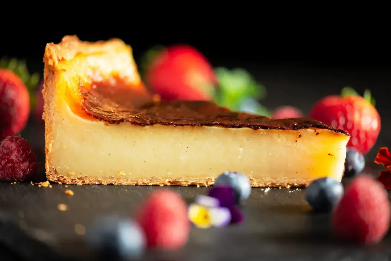 Tranche de flan pâtissier onctueux, avec une croûte dorée et des fruits rouges frais. Un délice pour les yeux et les papilles.