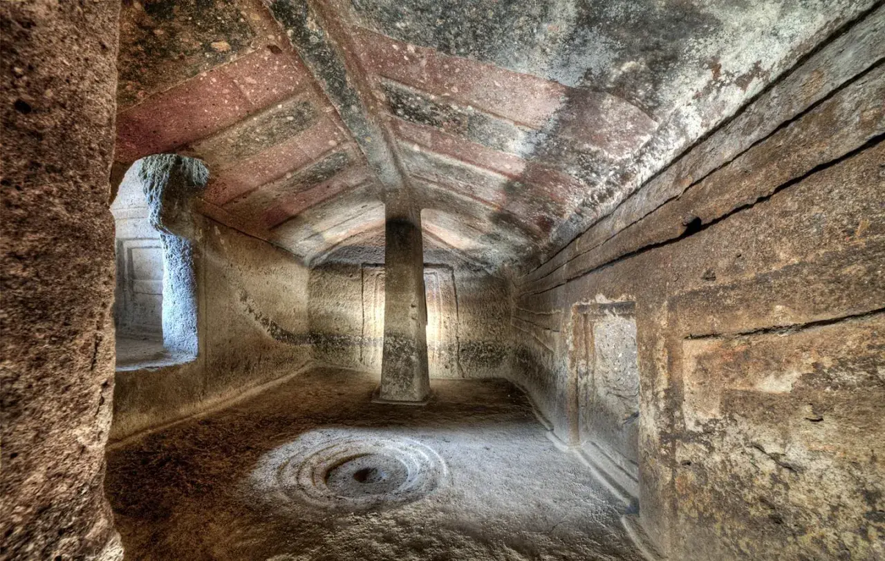 Interno di domus de janas dipinte, con pilastro centrale e decorazioni circolari sul pavimento.