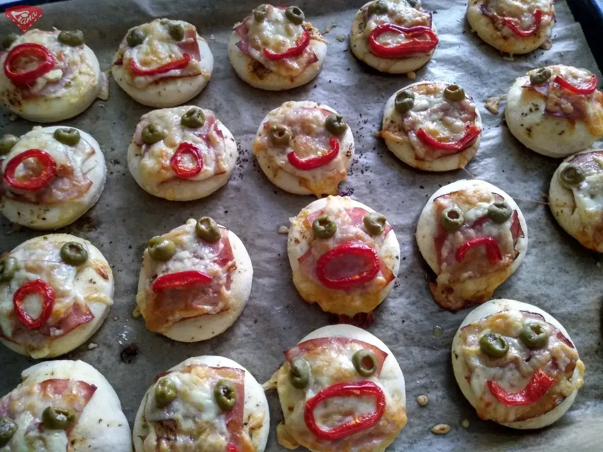 Lustige kleine Pizzen mit Olivenaugen und Paprikamund, perfekt zum glutenfrei essen.