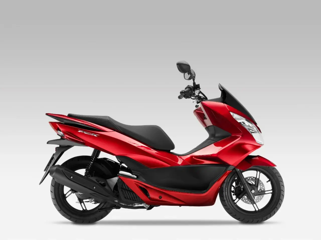 Czerwony skuter Honda PCX 125 na białym tle, widok z boku.