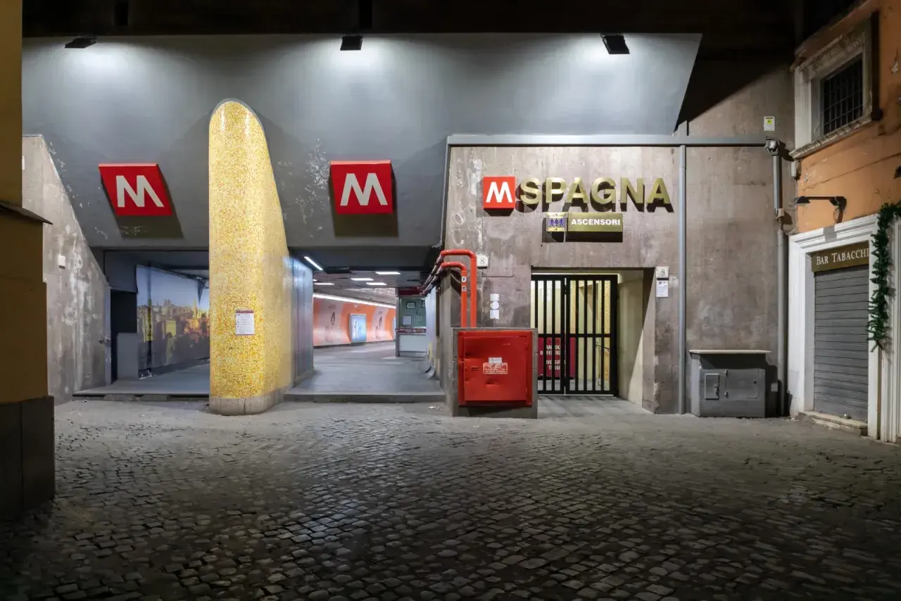 Ingresso della stazione metro Spagna a Roma, con insegna luminosa e pavimentazione in sampietrini.