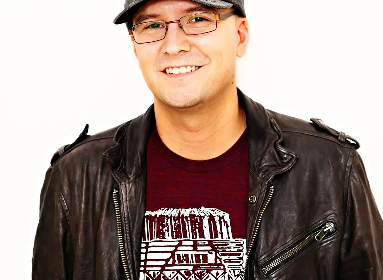 A smiling man in a leather jacket and cap, possibly inspired by the creative spirit behind Luke Laird songs.