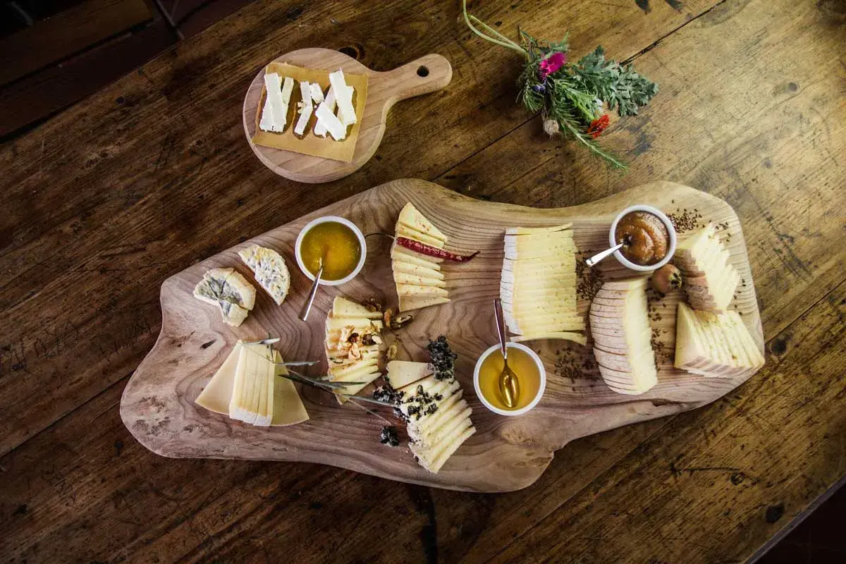 Assaggio di formaggi su tagliere rustico, ideale per un corso assaggiatore formaggi. Diverse varietà con miele e confetture.