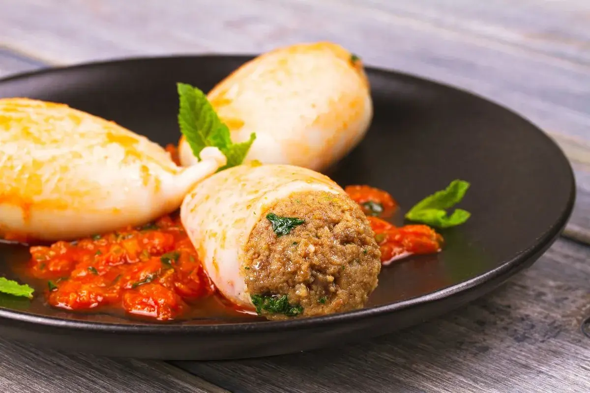 Calamari ripieni in friggitrice ad aria, serviti con salsa rossa e menta fresca. Un piatto gustoso e leggero.
