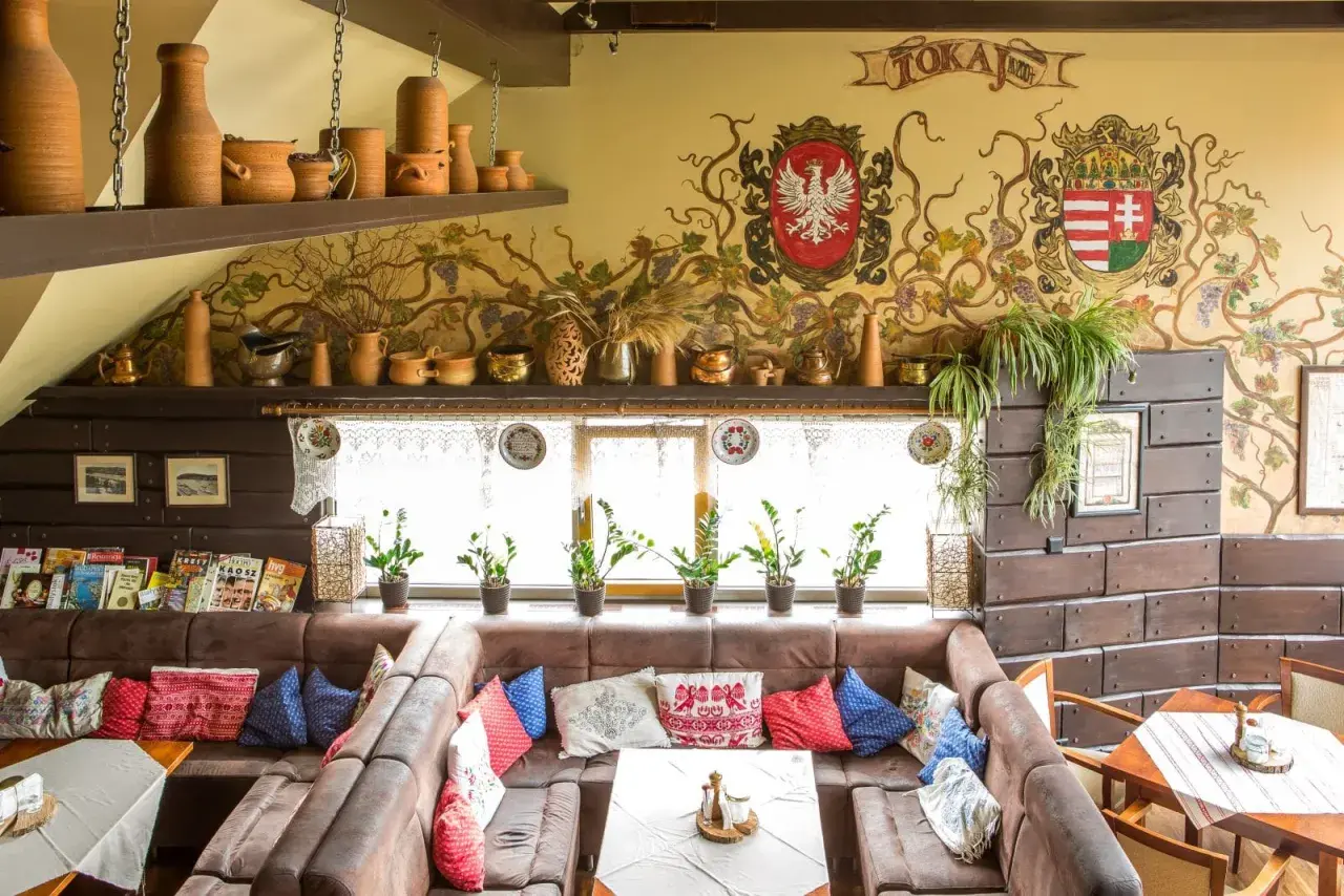 Wnętrze tokaj restauracja węgierska menu. Wygodne kanapy, ozdobne malowidła na ścianie i ceramiczne naczynia tworzą przytulną atmosferę.