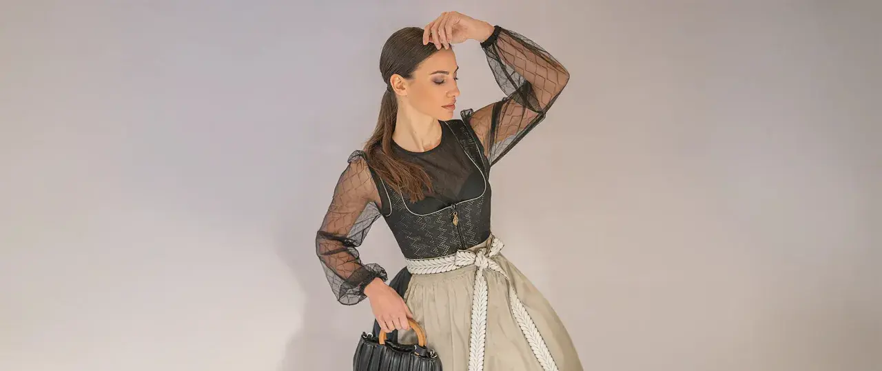 Frau im modernen mini dirndl extra kurz mit transparentem Oberteil und auffälliger Schürze.
