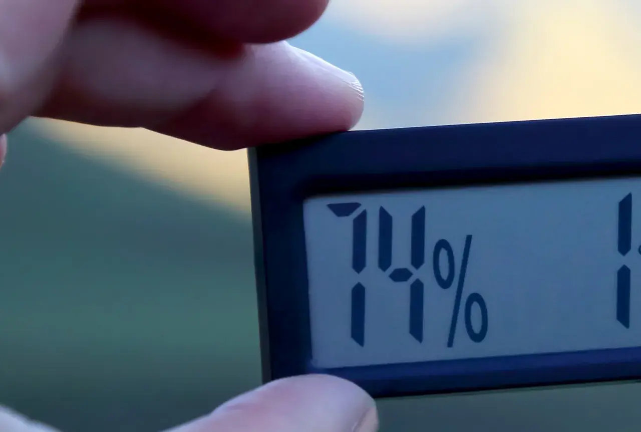 En digital hygrometer visar 74%, vilket indikerar hög luftfuktighet inomhus.