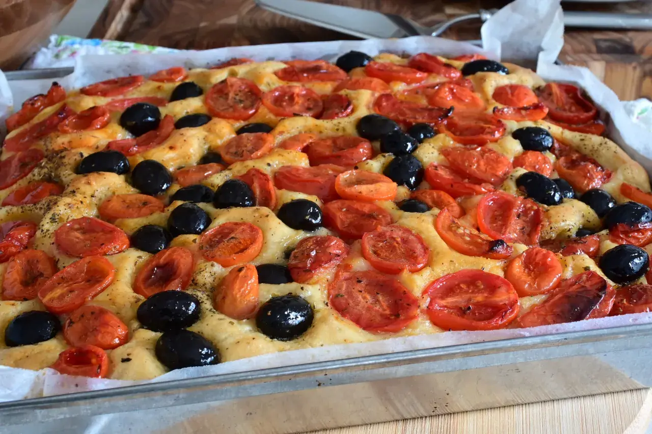 Focaccia con pomodorini e olive nere, un'esplosione di sapori che ricorda la semplicità di un pasto come quello di Rossella, pane e cioccolato.