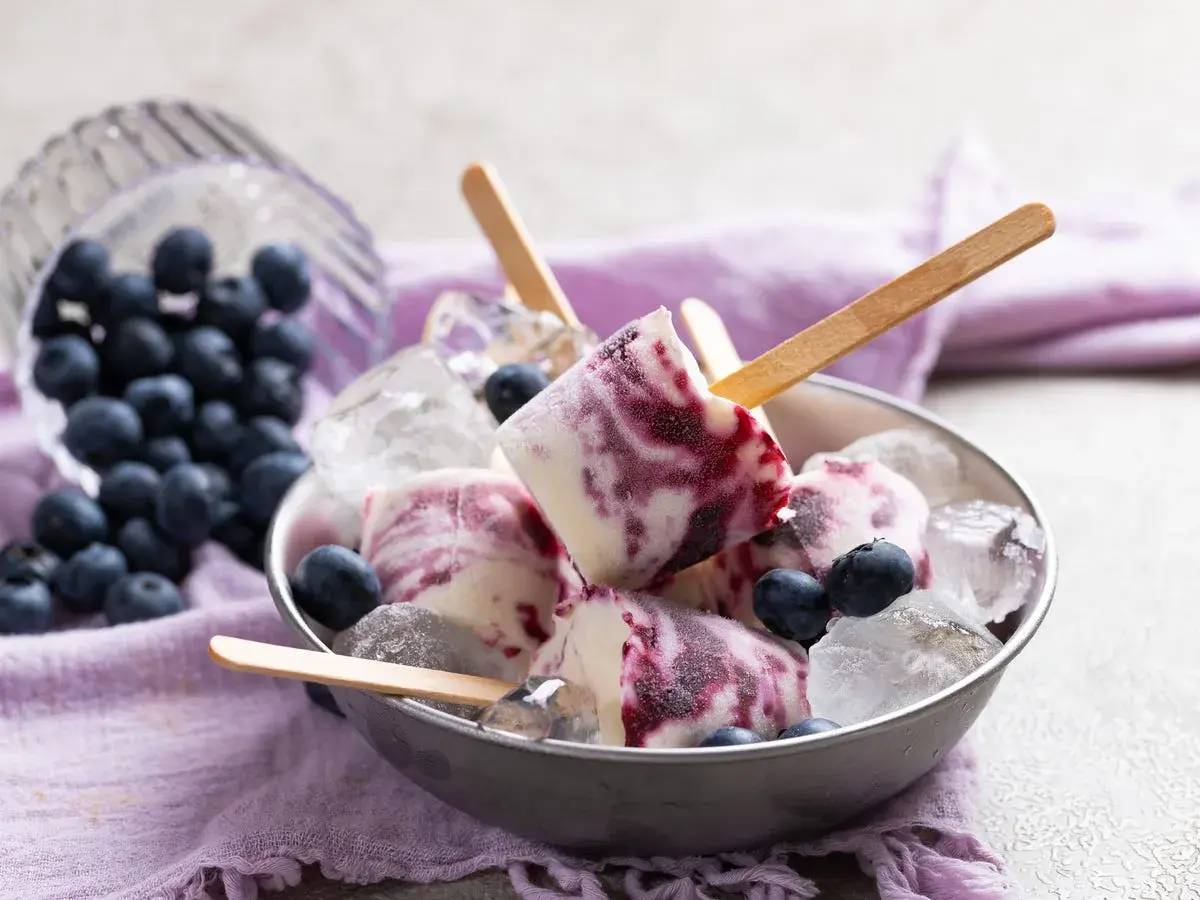 Gelato con yogurt greco e mirtilli, servito in una ciotola con ghiaccio e mirtilli freschi.