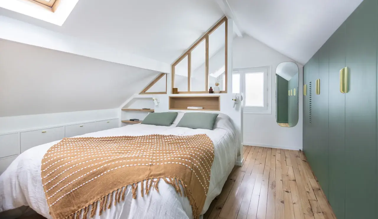 Suite parentale sous comble avec salle de bain et dressing. Un lit douillet, des rangements intégrés et une verrière style verrière d'atelier apportent charme et fonctionnalité.