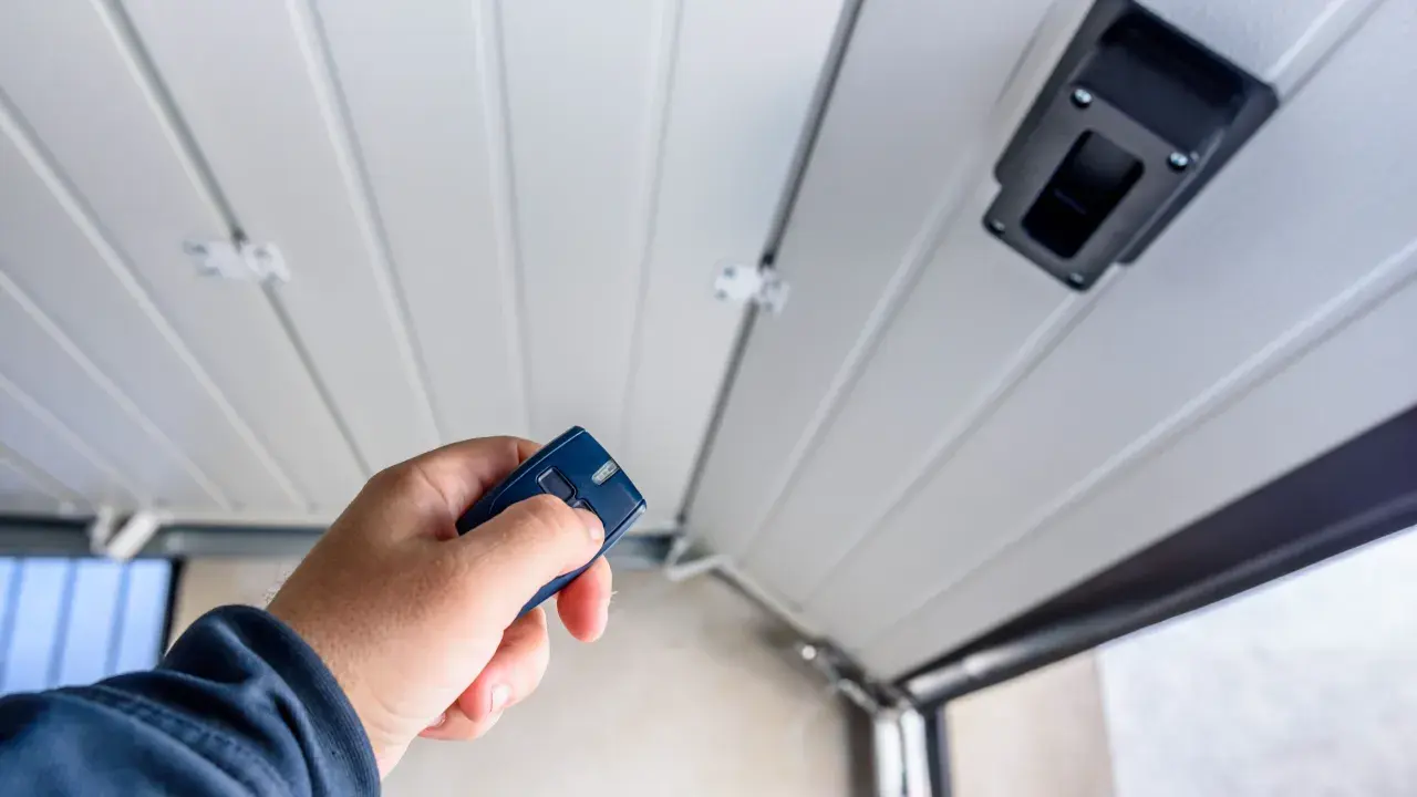 Main tenant utilise une télécommande pour motoriser une porte de garage.