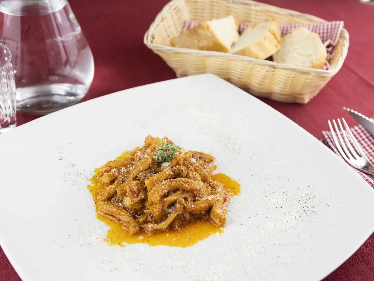 Un piatto di trippa alla fiorentina, saporita e profumata, servita su un piatto bianco con una spolverata di parmigiano.