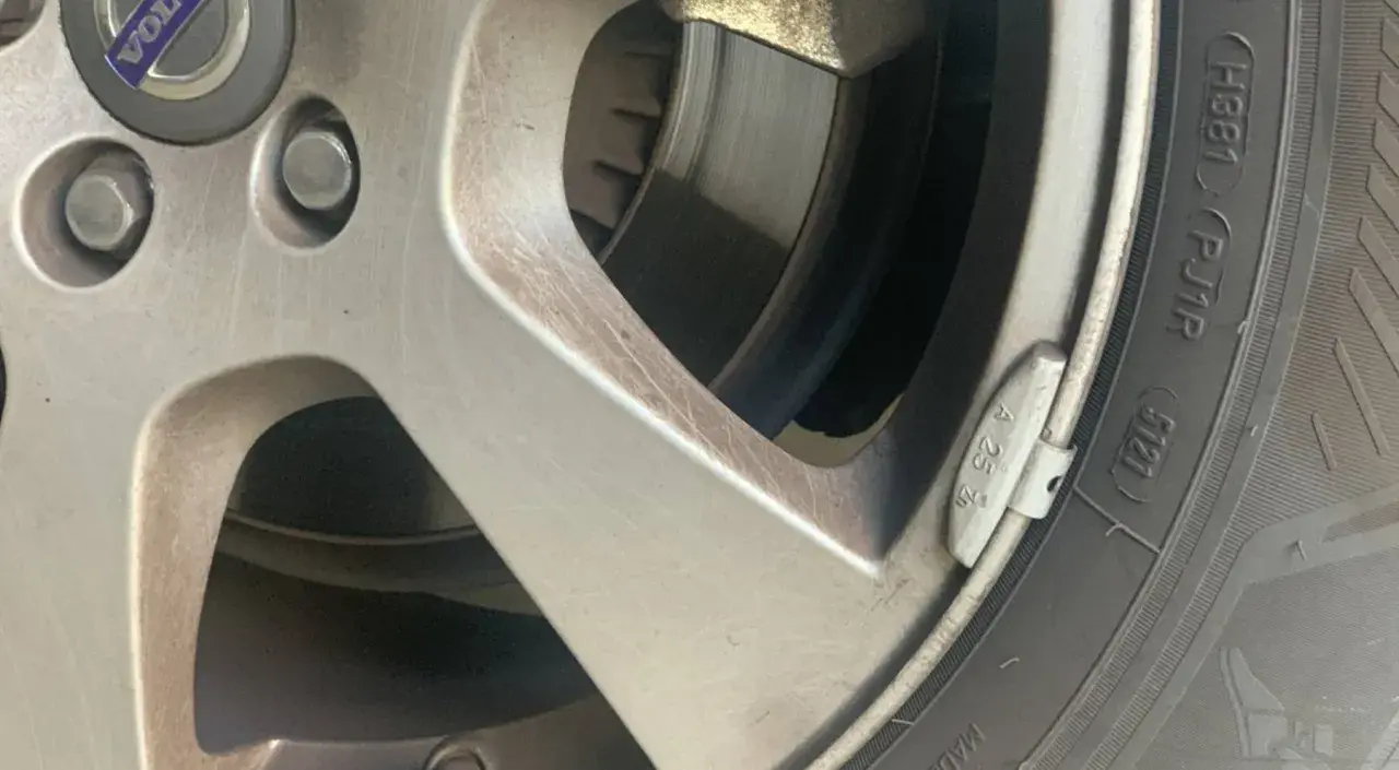 Detalle de una llanta de coche con un plomo de equilibrado de ruedas visible.