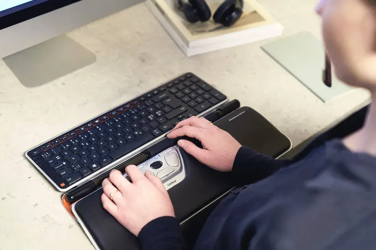 Mains sur un clavier et une souris ergonomique, des pointeurs de souris pour un confort optimal.