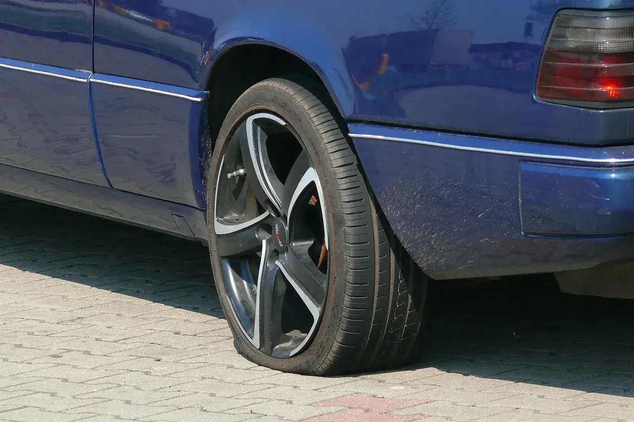 Pneu à plat sur une voiture bleue. Une situation qui pourrait compliquer un recours achat voiture particulier.
