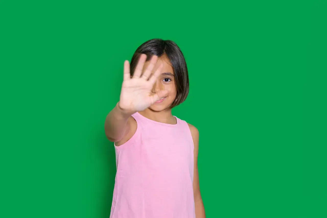 Niña de 4-5 años muestra timidez, cubriendo su rostro con la mano.