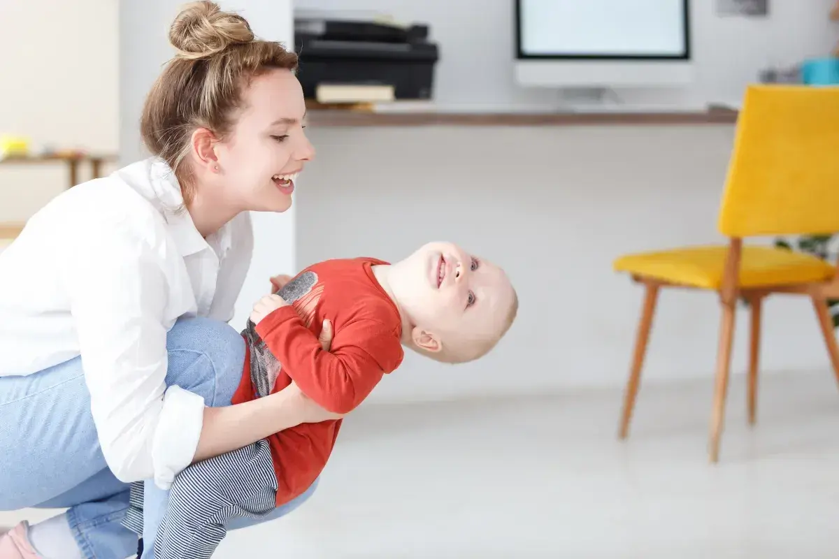 Szczęśliwa mama bawi się z dzieckiem, planując dopłatę do żłobka.