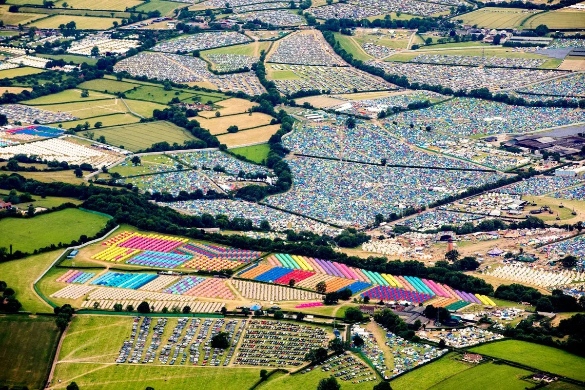 Aerial view of a vibrant Glastonbury map, showcasing a sprawling landscape of colorful tents and parked cars, a testament to the festival's immense scale.