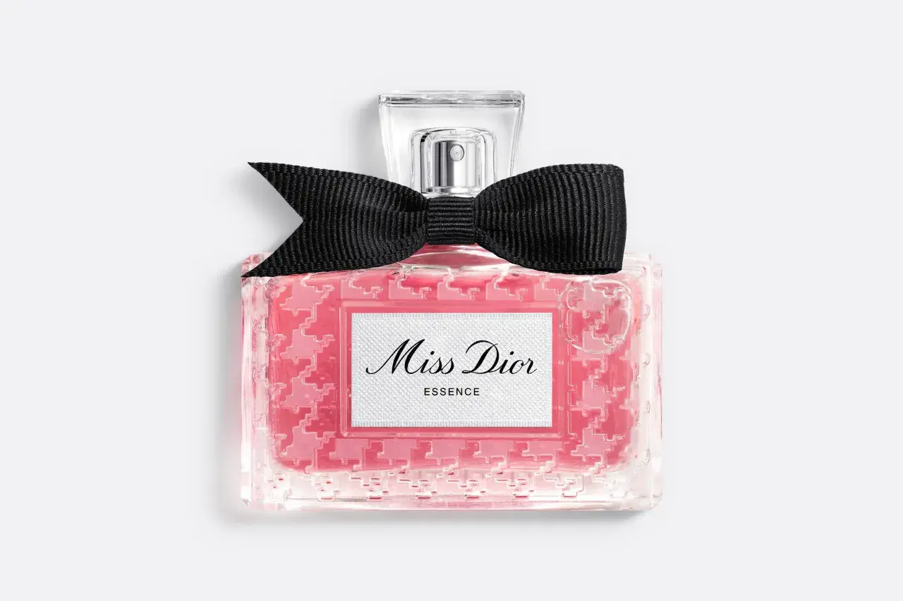 Różowy flakonik Miss Dior Essence z czarną kokardką, pachnący jak soczysta wiśnia.