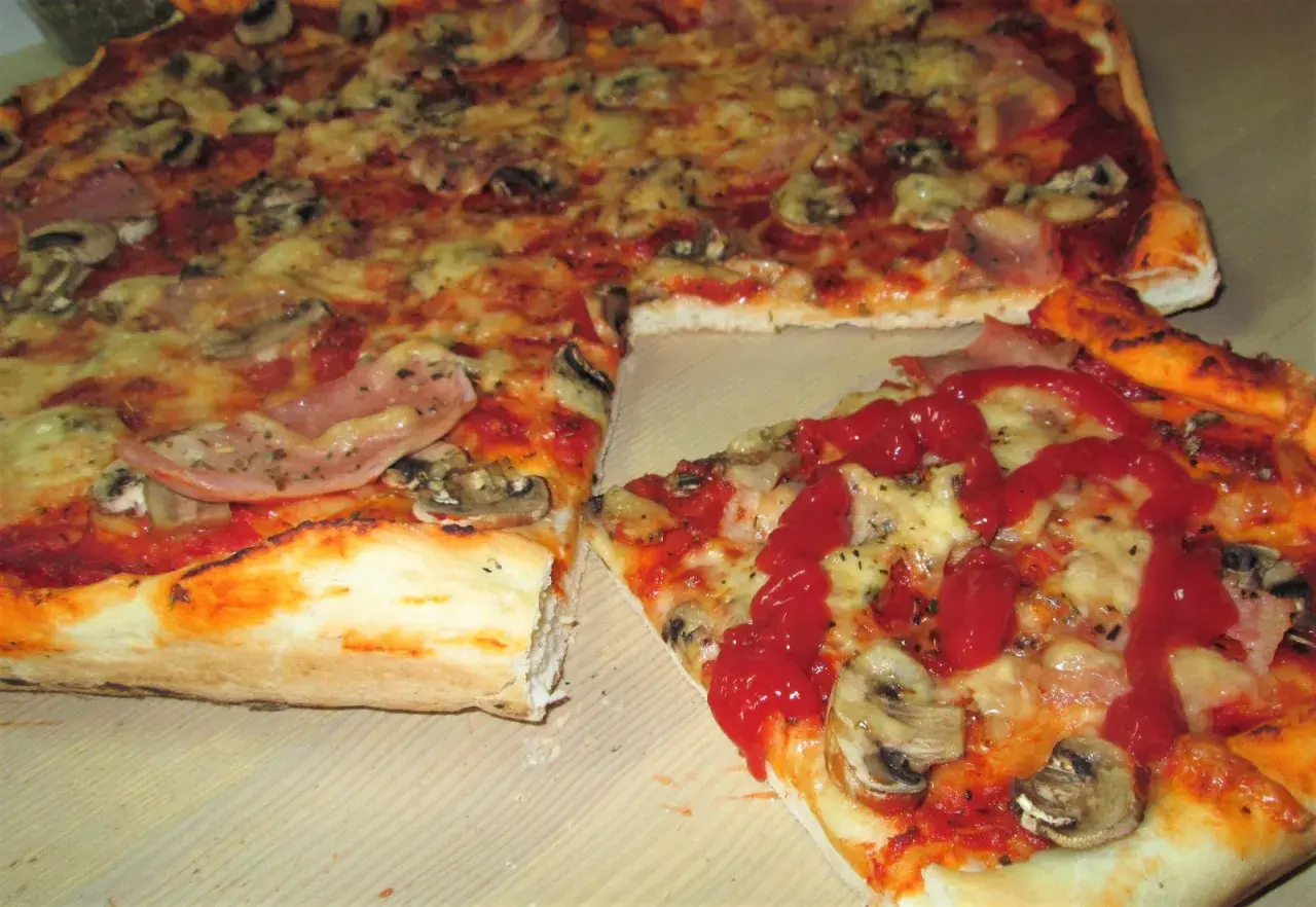 Domowa pizza z pieczarkami i szynką, polana ketchupem. Idealna inspiracja, jak zrobić pizzę, która zachwyci każdego.